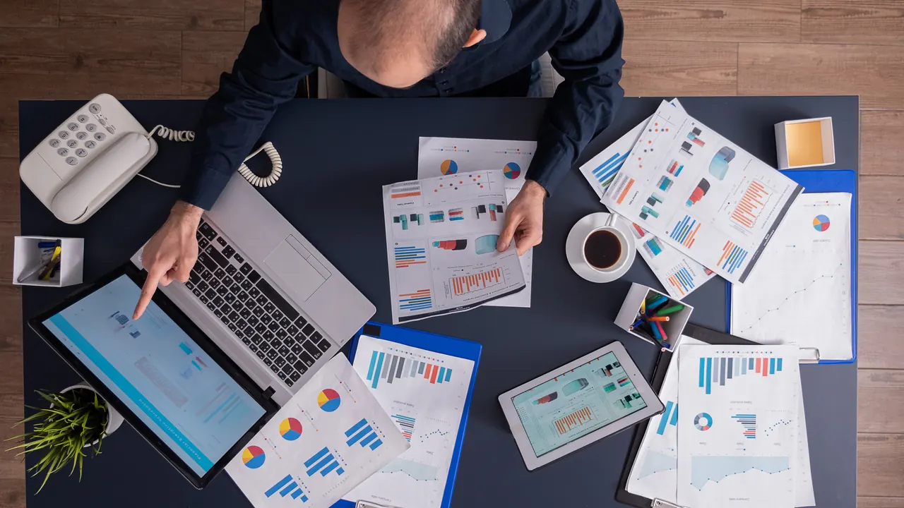 Desk with financial statements and charts seen from above