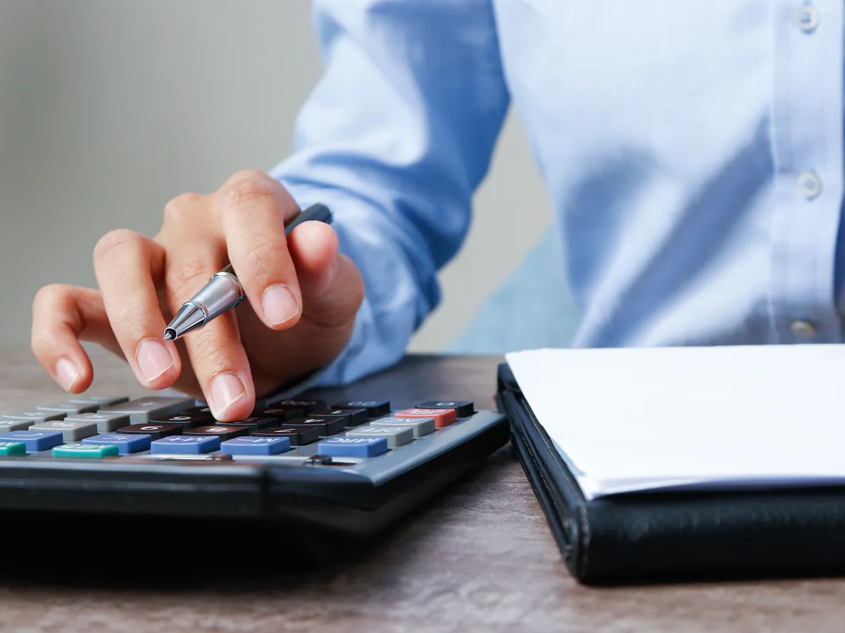 Accountant calculating taxes with a calculator and documents