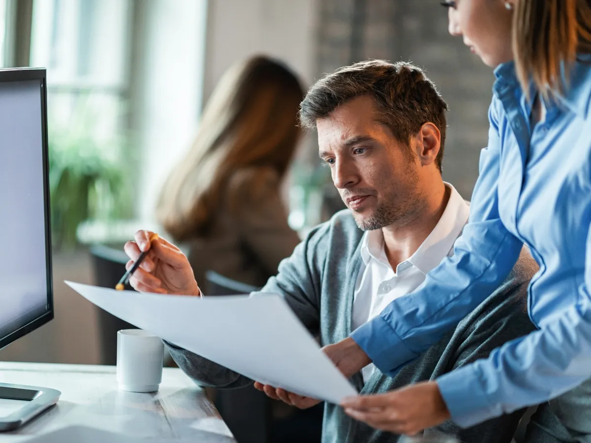 Two auditors reviewing printed financial statements in an office