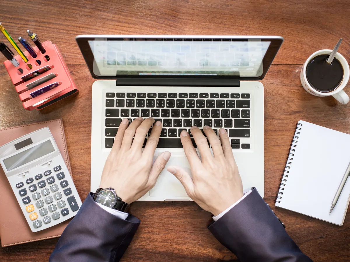 Desk with a laptop, a calculator and an accounting notebook