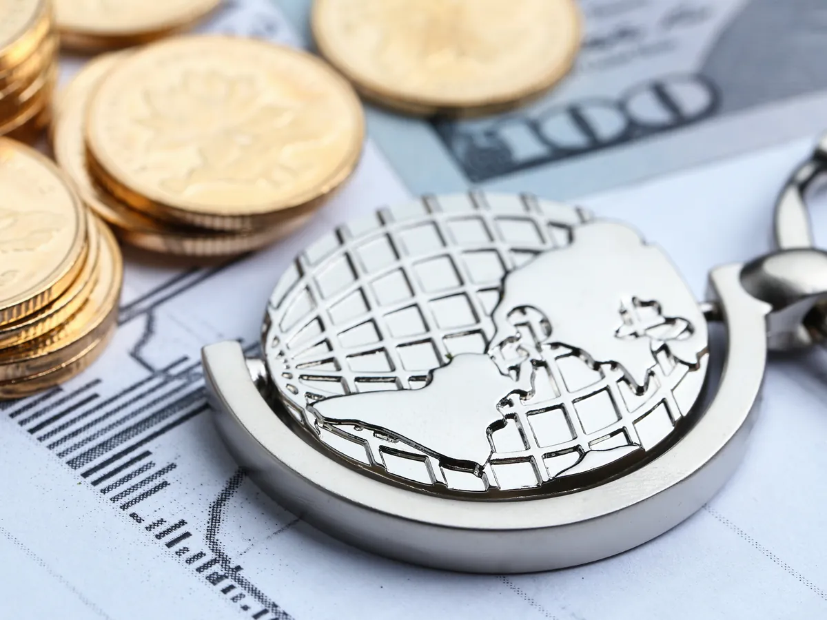 Metal globe on top of coins and financial reports